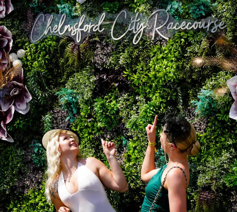 Two ladies posing in front of a living wall.